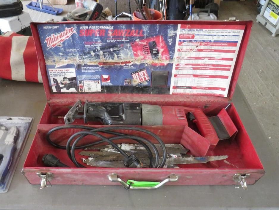 Red Milwaukee Super Sawzall in a red metal case, open on a table.