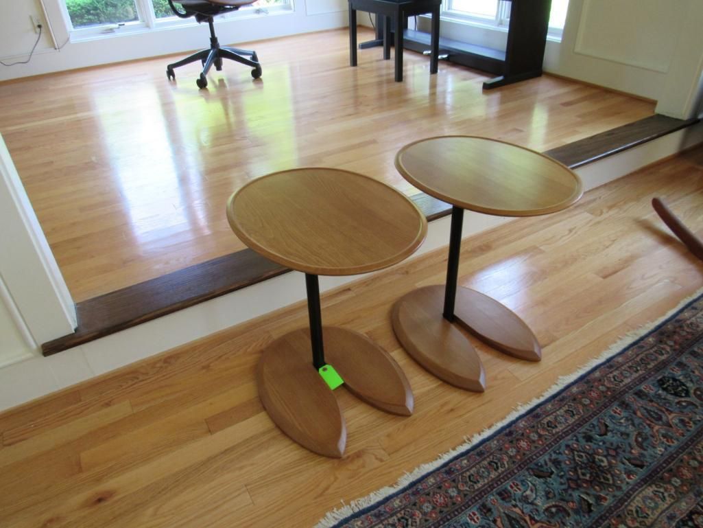 Two small wooden tables with round tops and leaf-shaped bases on a hardwood floor.