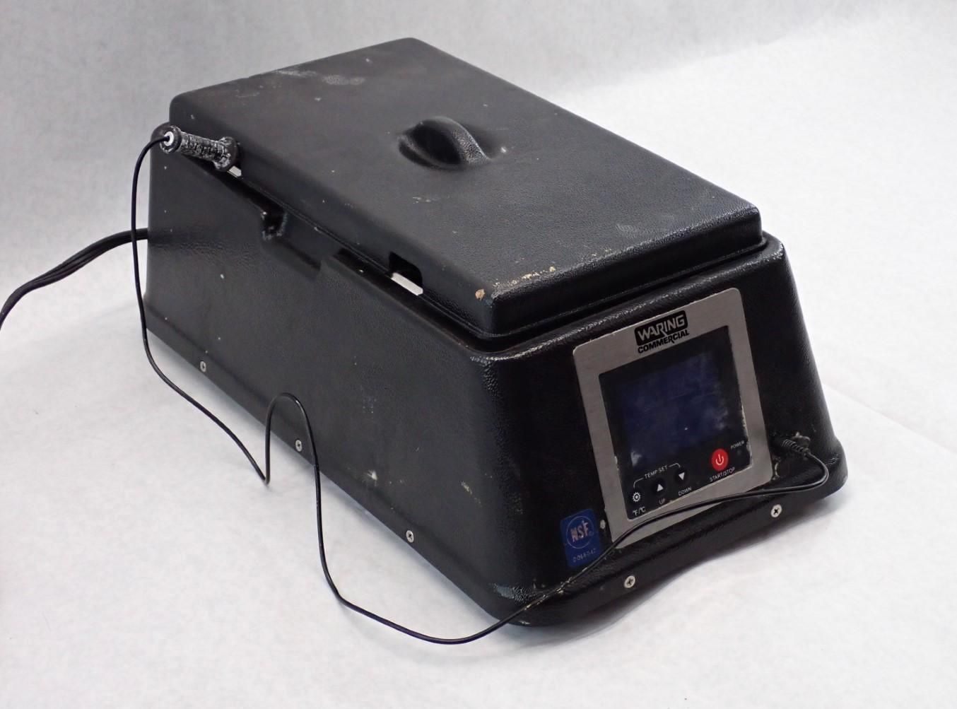 Black laboratory device with a lid, control panel, and attached wires.