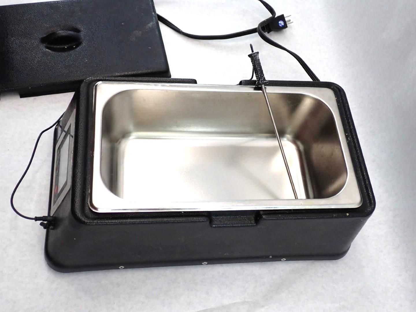 Black electric wax melter with stainless steel interior, lid off, temperature probe attached.