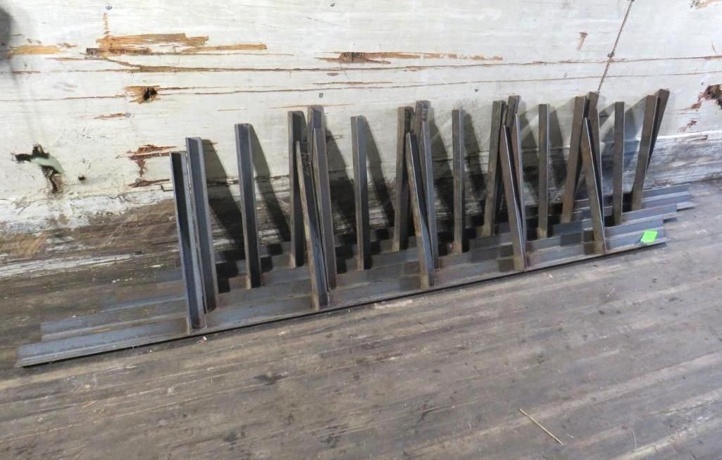 Steel pieces arranged vertically on a horizontal metal base, set against a concrete wall.