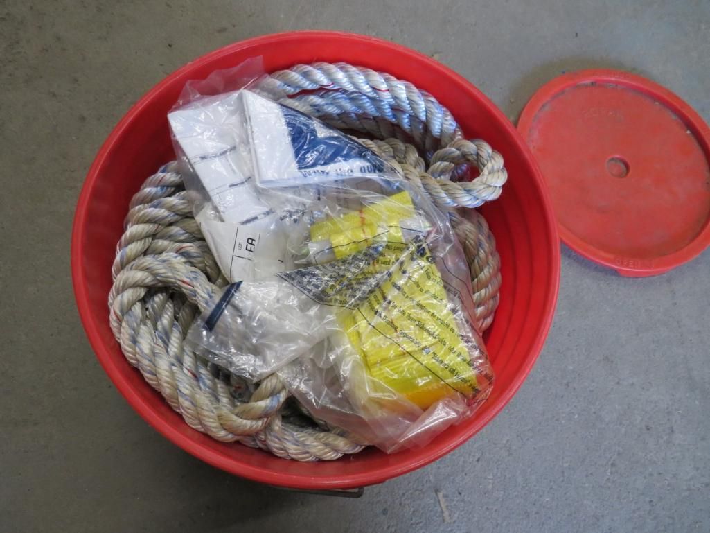 Red bucket with rope and packaged items, lid to the side.