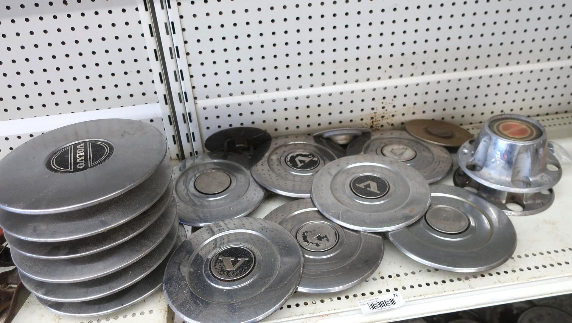 A collection of vintage metal hubcaps of various designs on a shelf.