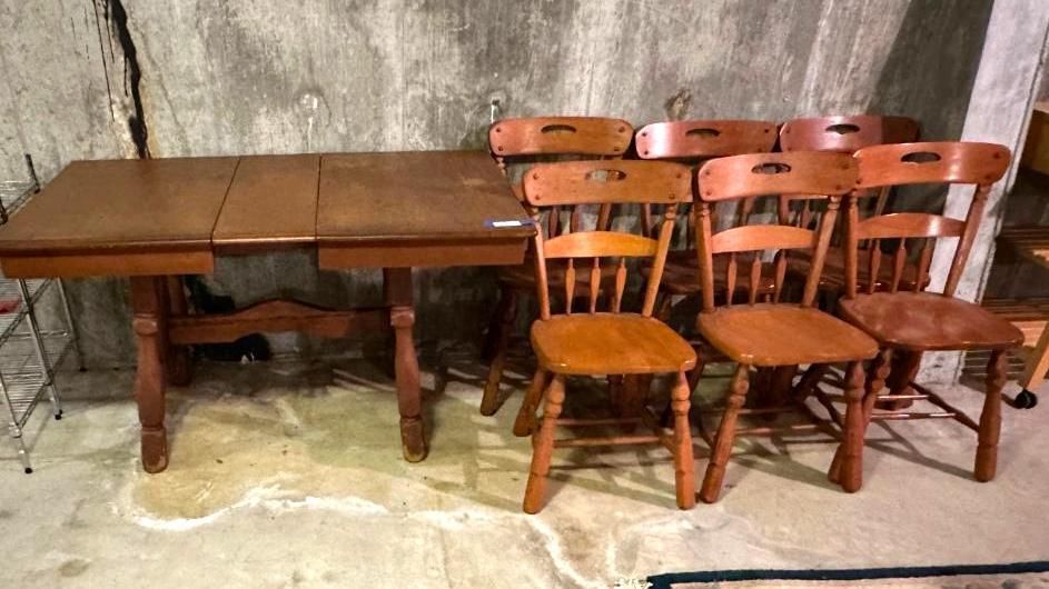 Wooden dining table with six chairs against a rough wall.