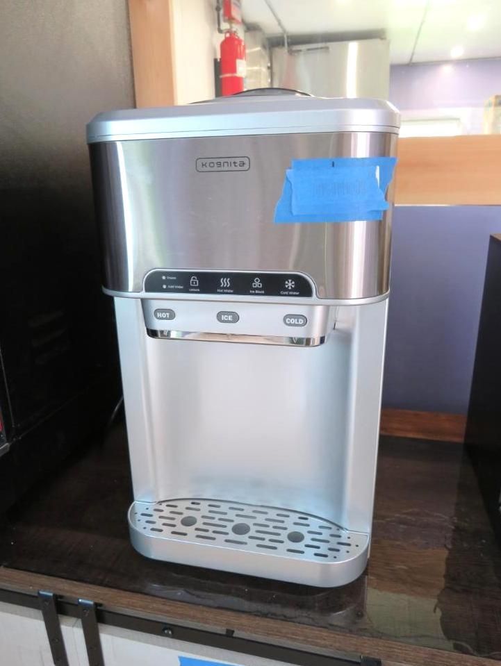 Silver and white water dispenser with buttons, on a counter.