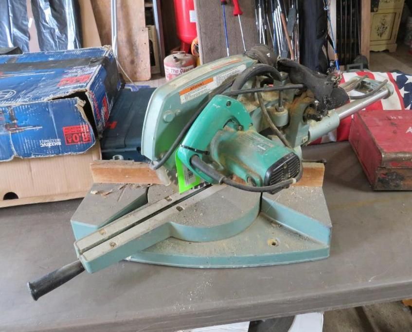 Green and gray miter saw on a table.