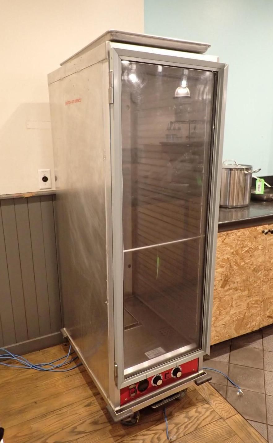 Stainless steel commercial food warmer on wheels, glass door, red controls.