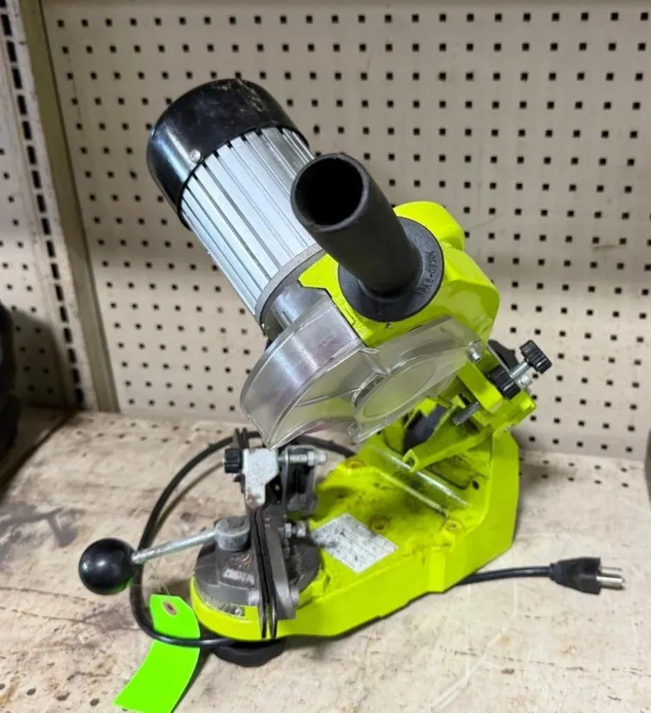 Bright green power tool with black handle and silver blade, sitting on a workbench in a pegboard workshop.