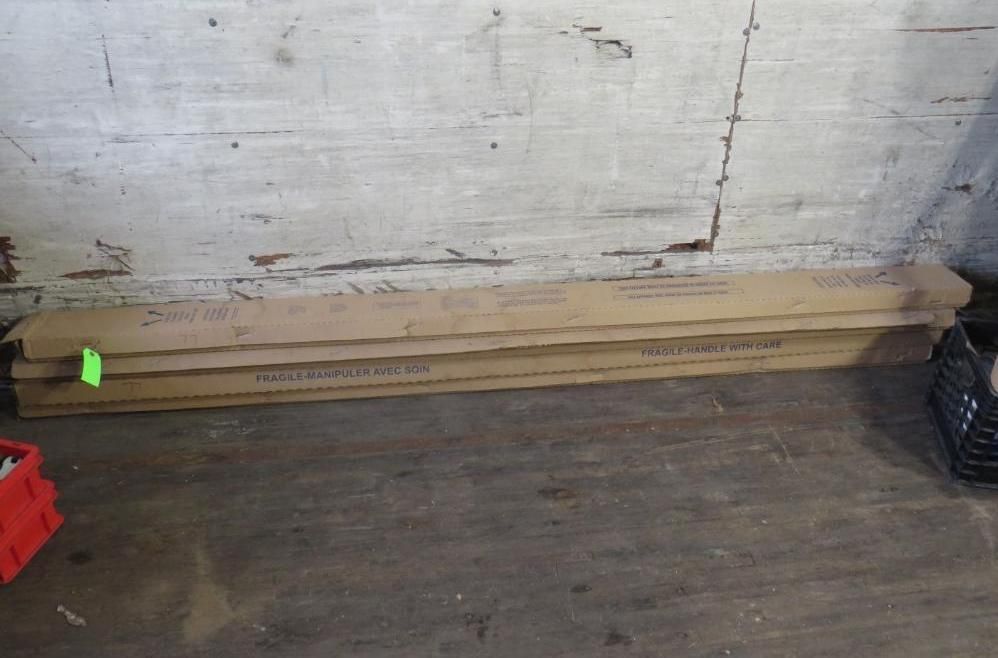 Stack of brown cardboard boxes on a wooden floor against a white wall.