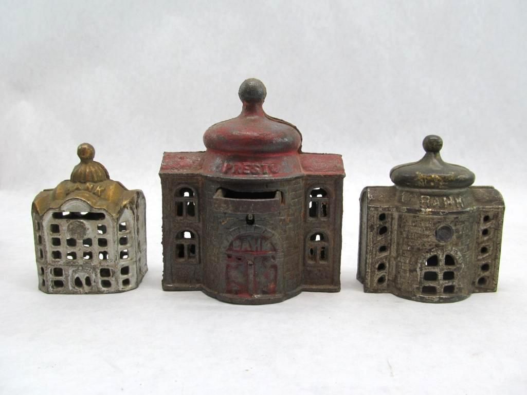 Three antique cast iron bank buildings in various colors.