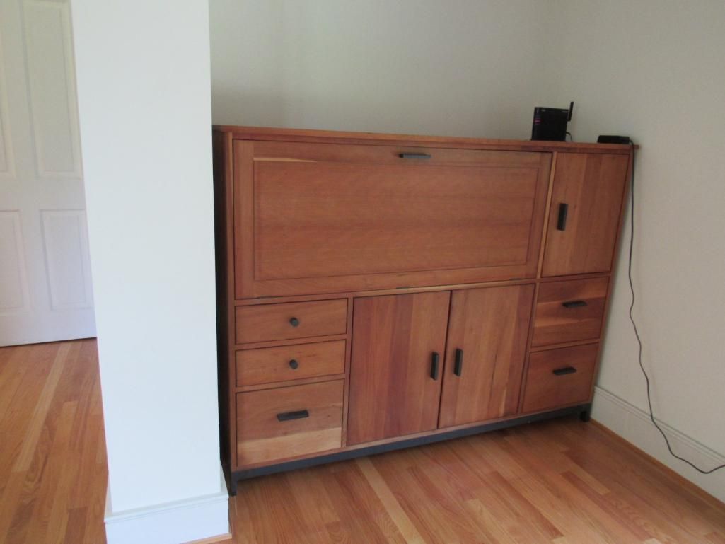 Wooden cabinet against white wall with drawers, doors, and a fold-out desk.