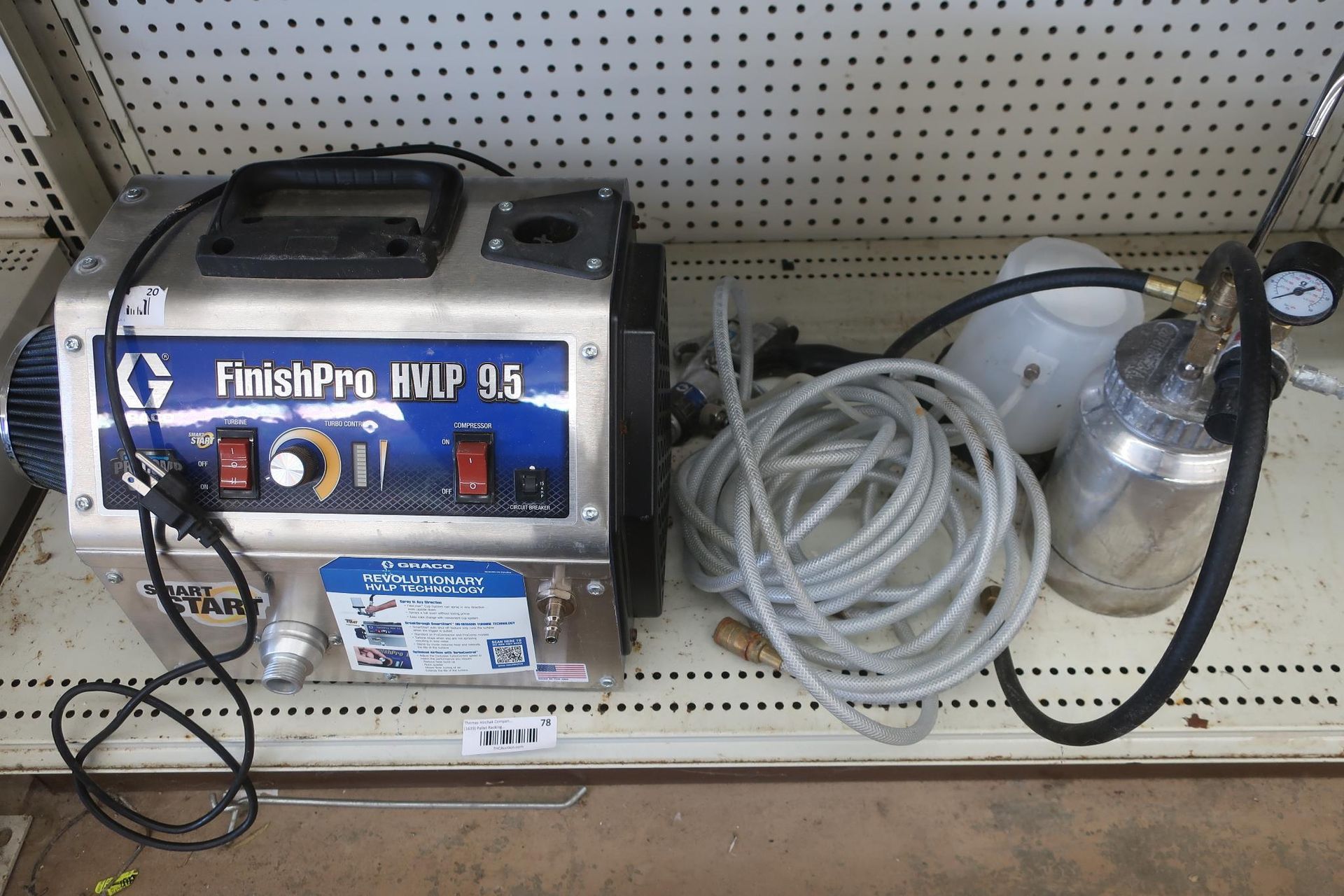 Graco FinishPro HVLP 9.5 paint sprayer on a shelf. Silver and blue machine with accessories.