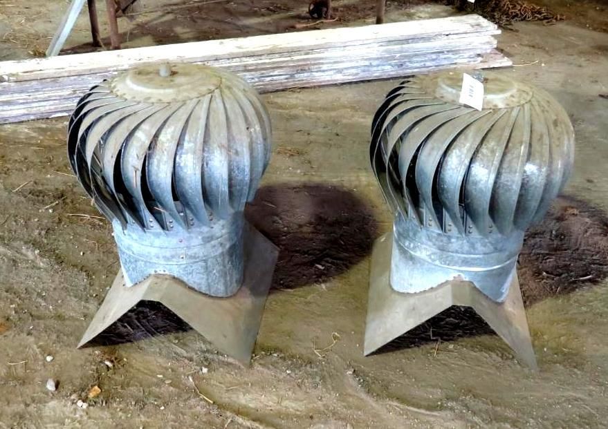 Two silver, metal turbine roof vents on a dirt surface.