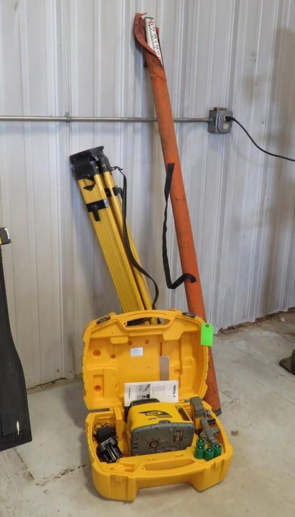 Yellow construction tools: a case, tripod, and carrying case, leaned against a white wall.