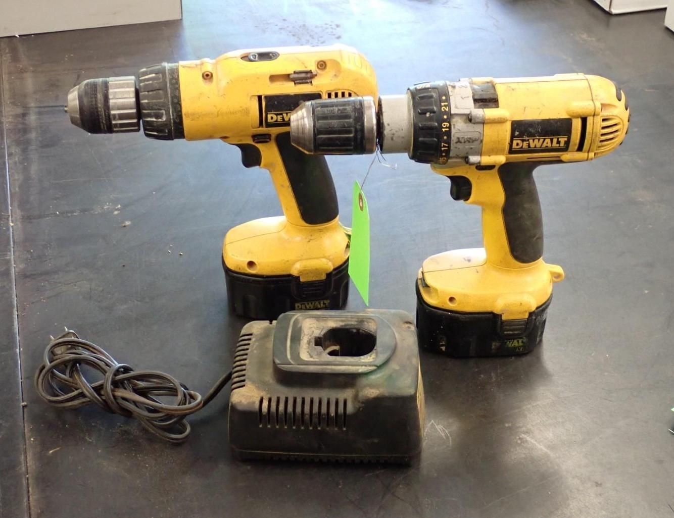 Two yellow DeWalt drills and a charger on a dark surface.