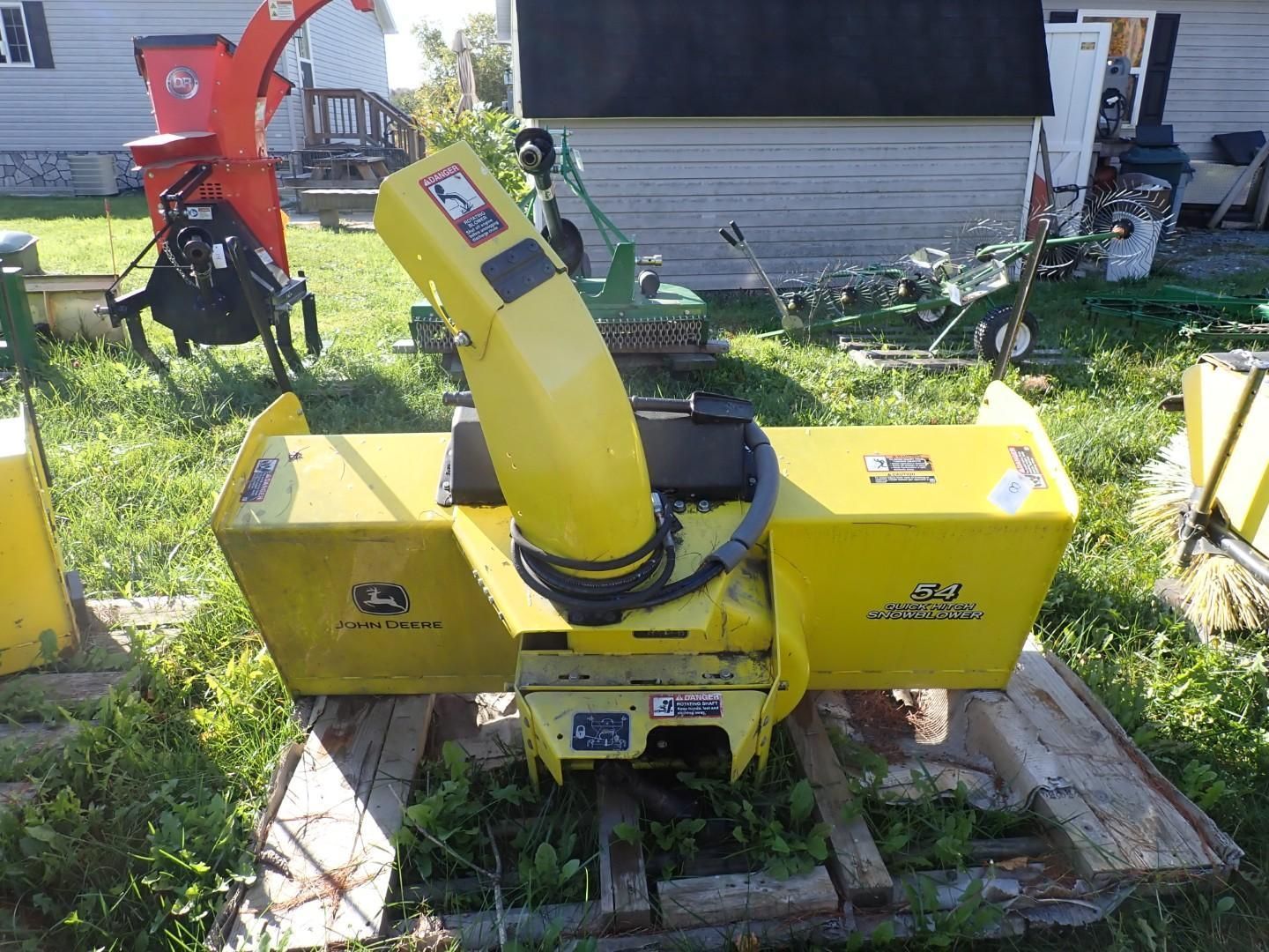 Yellow wood chipper on a pallet in a grassy yard, with a red machine behind it.