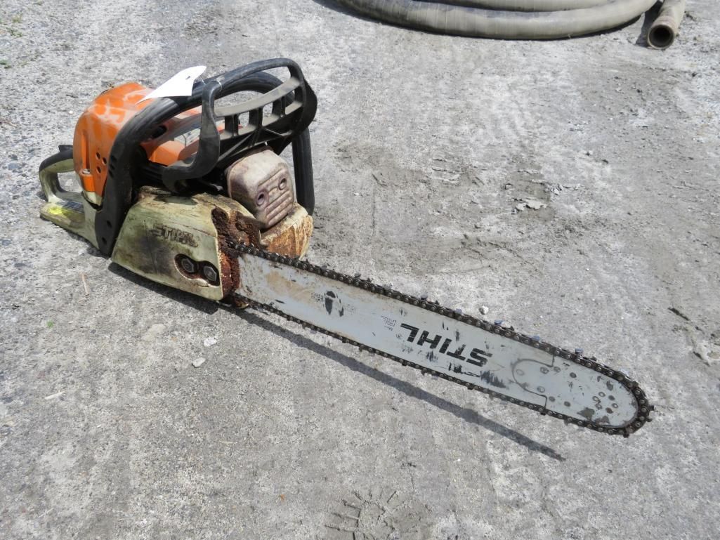 Orange and gray STIHL chainsaw on concrete.