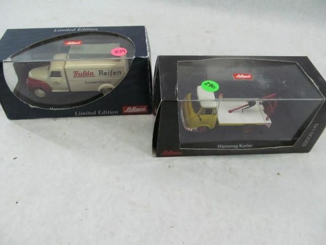 Two die-cast model trucks in boxes. One is cream and red, the other yellow. Both are in boxes.