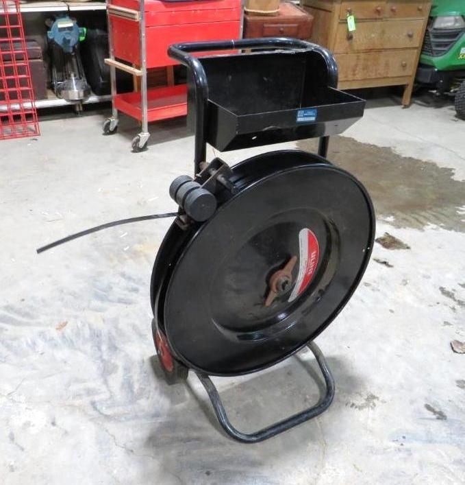 Black strapping cart with wheels and a small storage shelf.