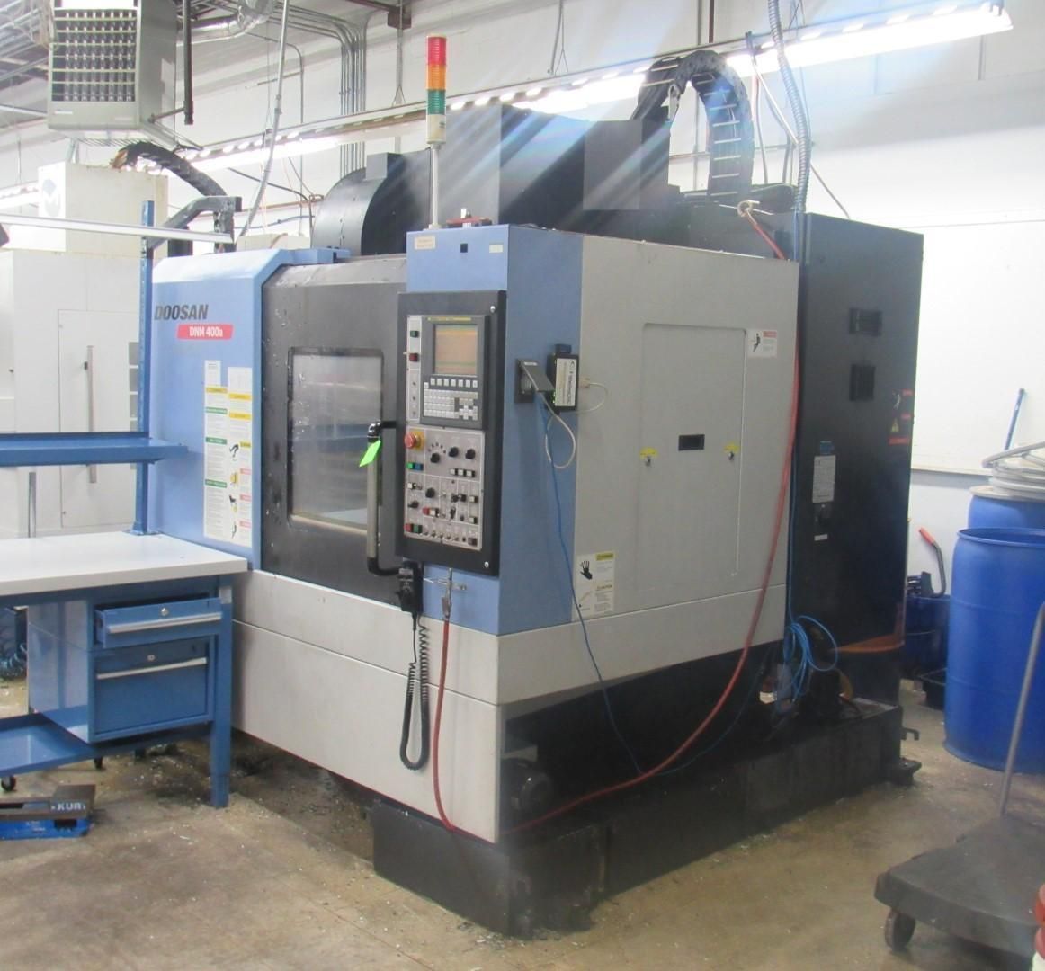 CNC milling machine in a workshop. Gray and blue machine with control panel.