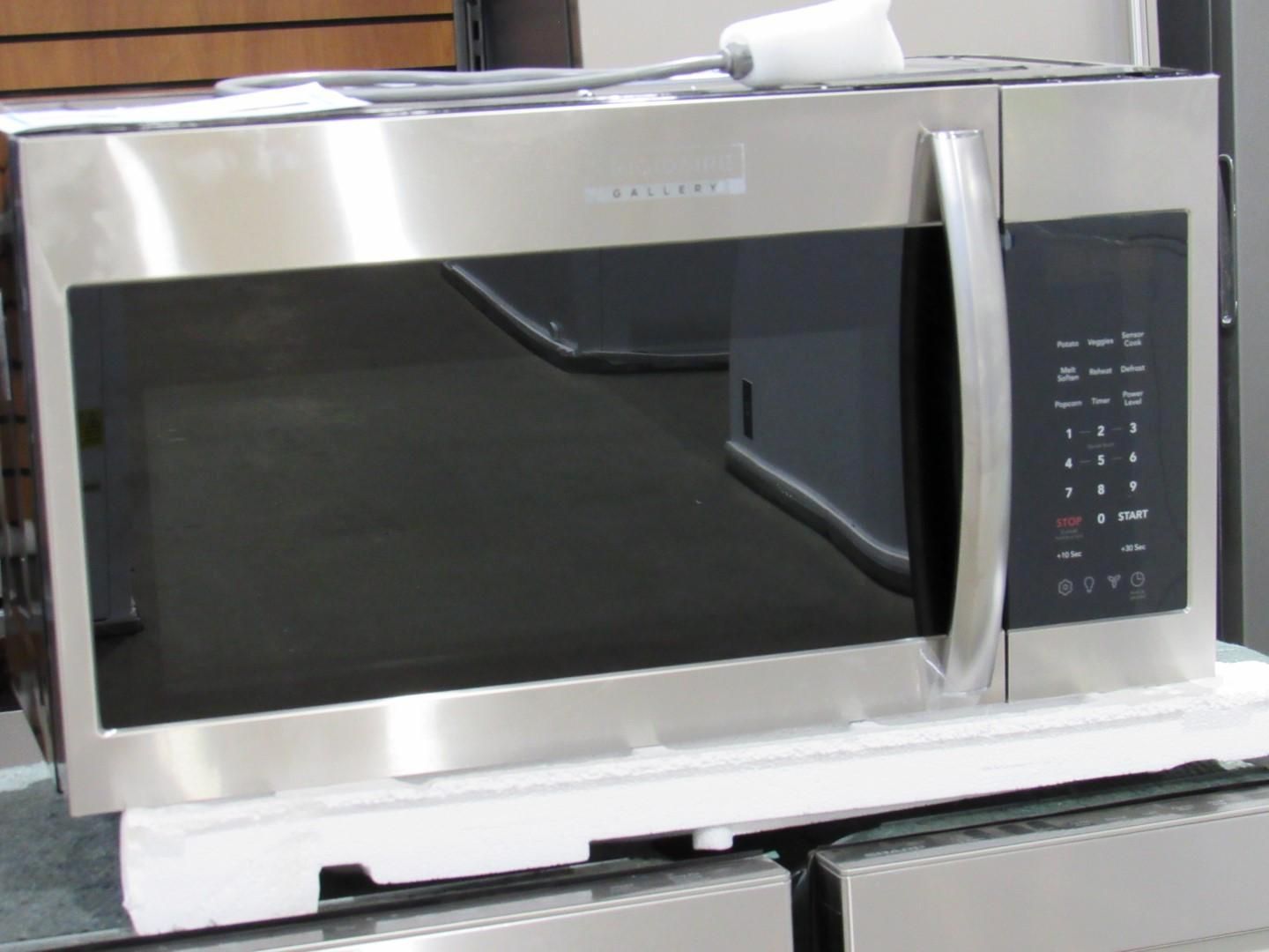 Stainless steel microwave with black door and control panel, displayed on a shelf.