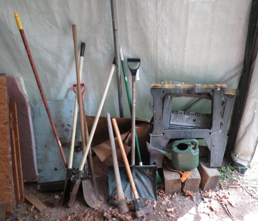 Various shovels and tools leaning against a wall.
