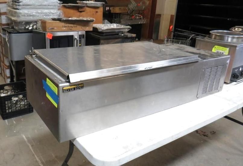 Stainless steel commercial food cooler on a white table.