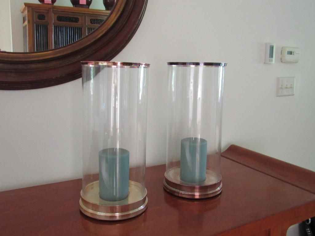 Two glass candle holders with blue candles on a wooden table.