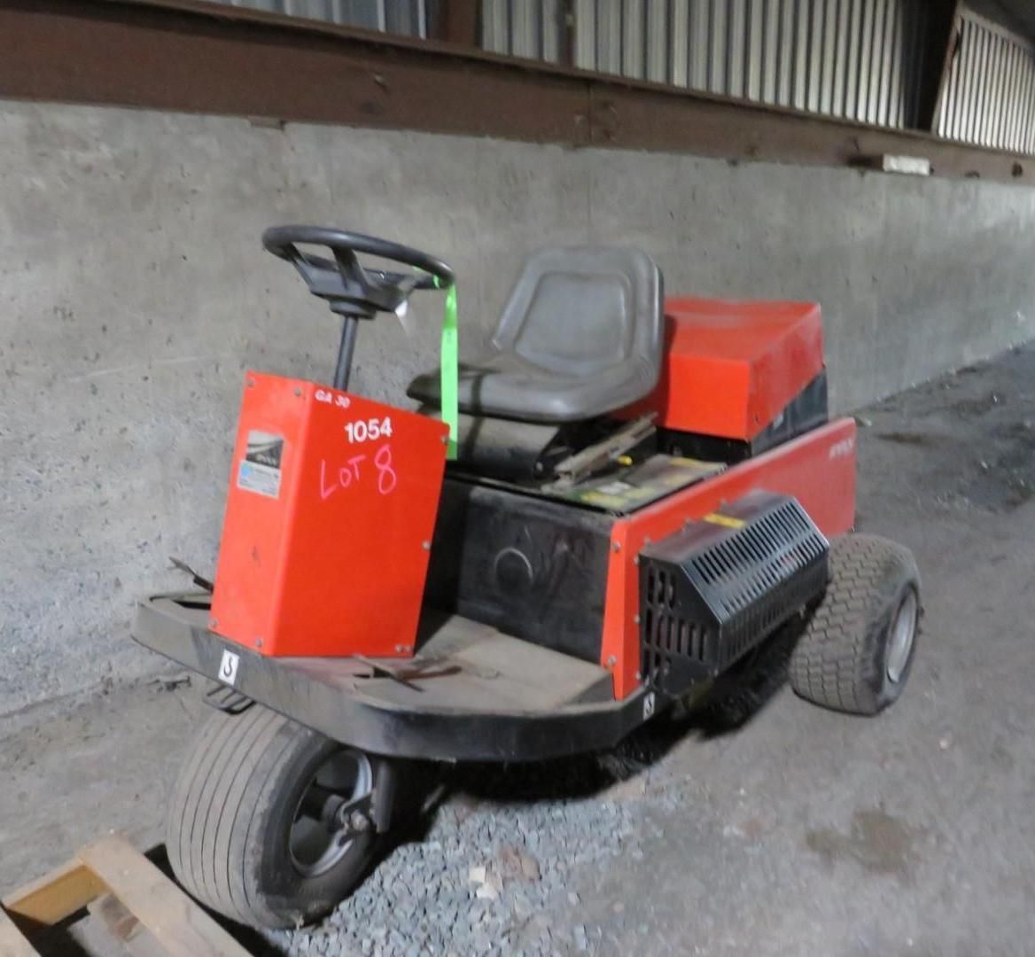 Orange riding mower in a warehouse, with black tires and seat.