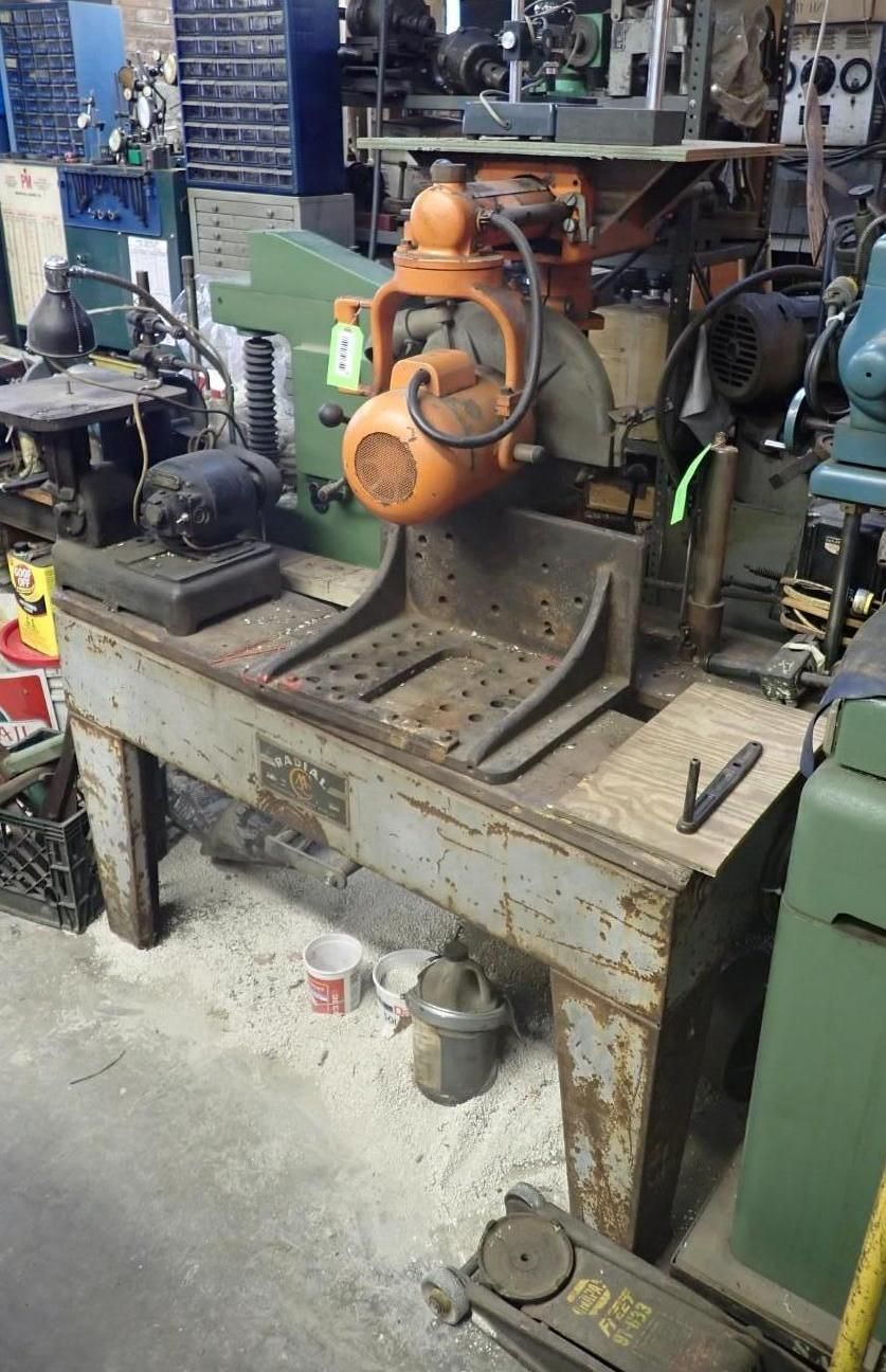 Orange radial arm saw on a metal table in a workshop.
