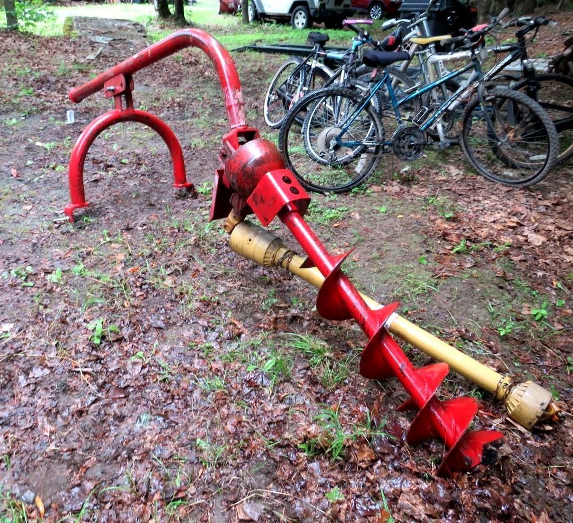 Red and yellow auger drill on ground.