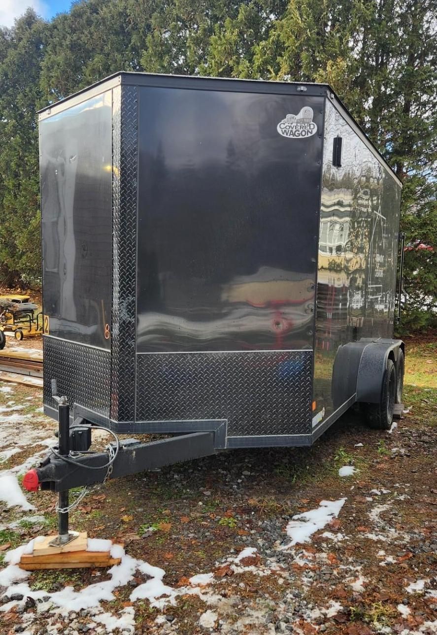 Black enclosed cargo trailer parked outside on a grassy area.
