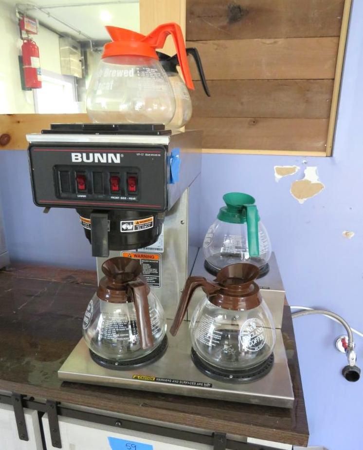 Coffee maker with orange and brown carafes, set on a counter.