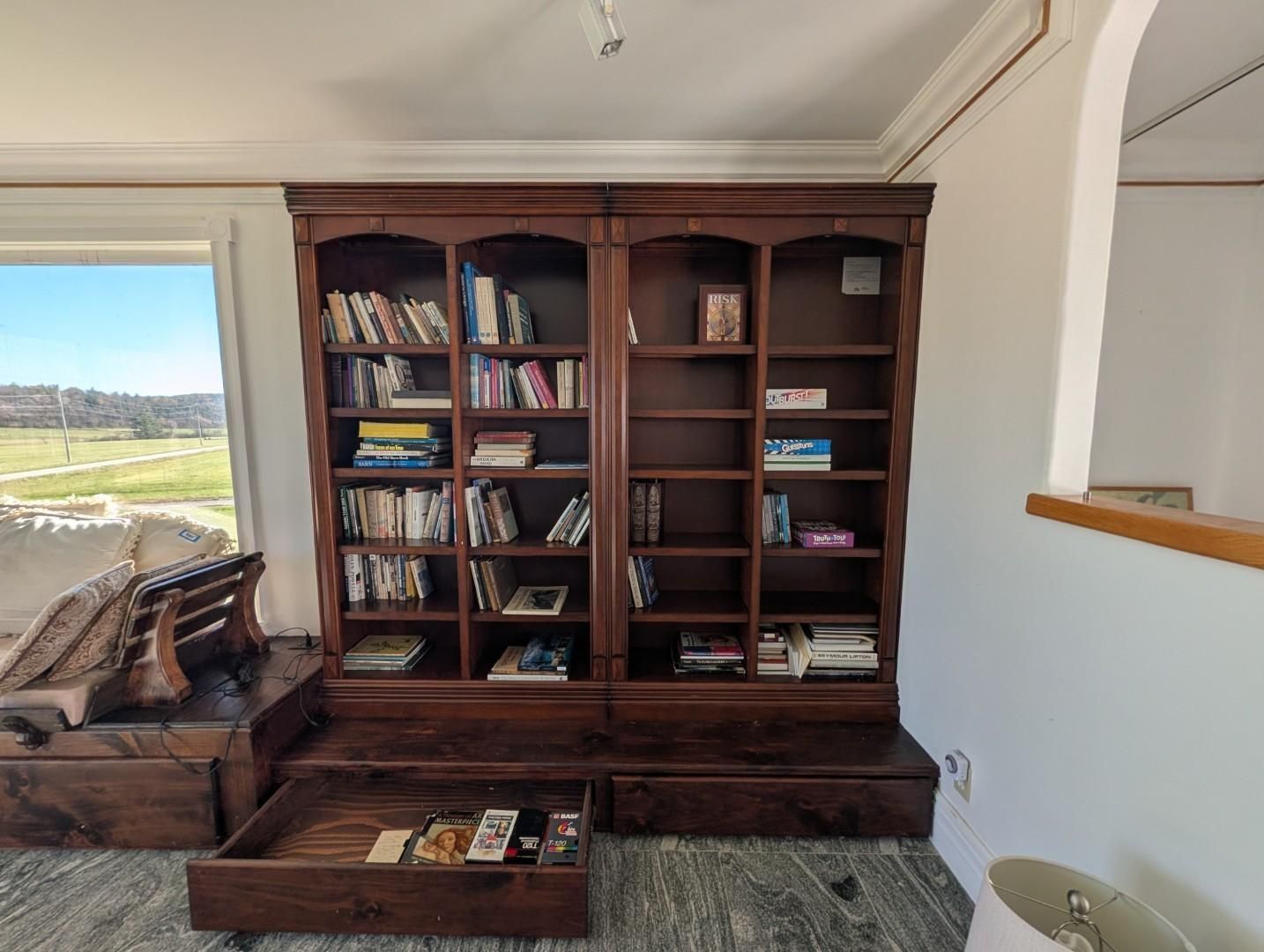 Wooden bookshelf with books beside a window in a bright living room