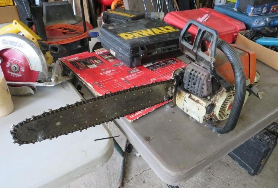 A dirty chainsaw, a circular saw, and a toolbox.