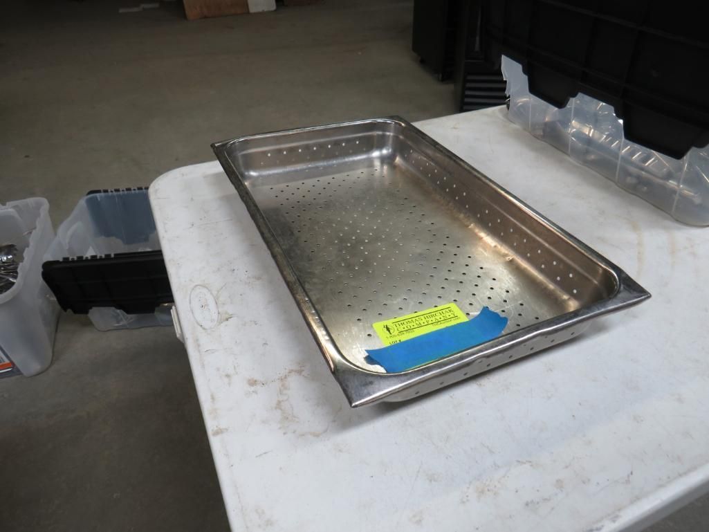 Stainless steel perforated pan on a white table. It has a yellow and blue tape.