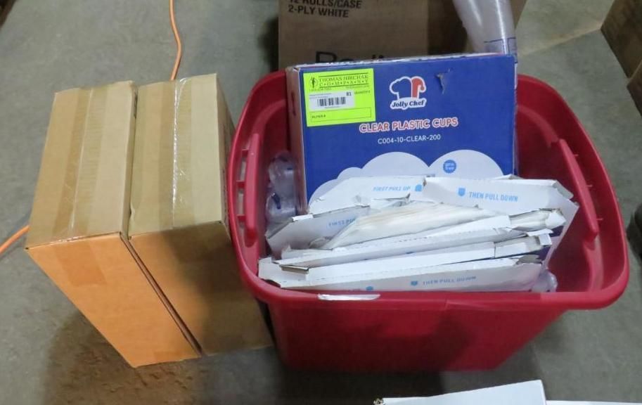 Two cardboard boxes and a red bin filled with blue and white boxes and packaging on a floor.