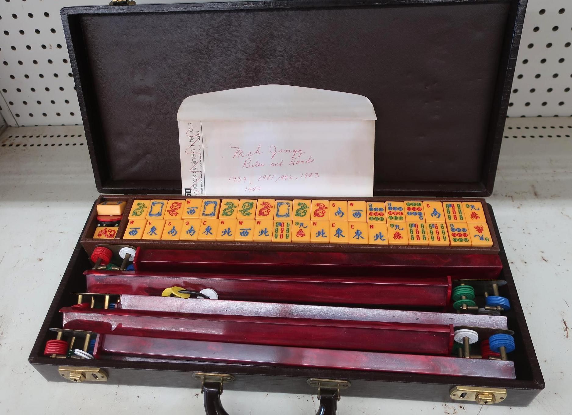 Mahjong set inside a brown case; tiles, racks, and accessories visible.