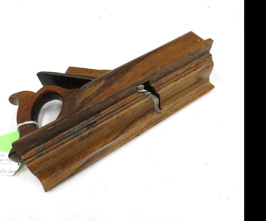 Wooden hand plane tool, brown wood, with blade, lying on white surface.