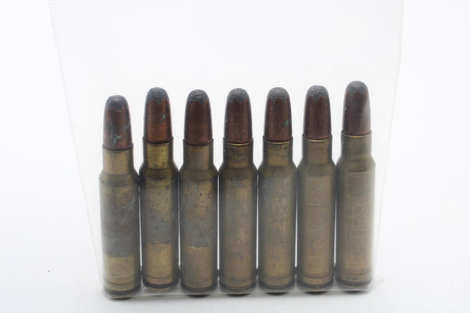 Seven old brass-colored bullets standing upright on a white background