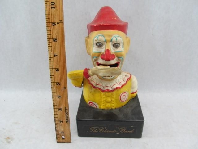 Clown bank with red hat, yellow shirt, and black base; beside a ruler.