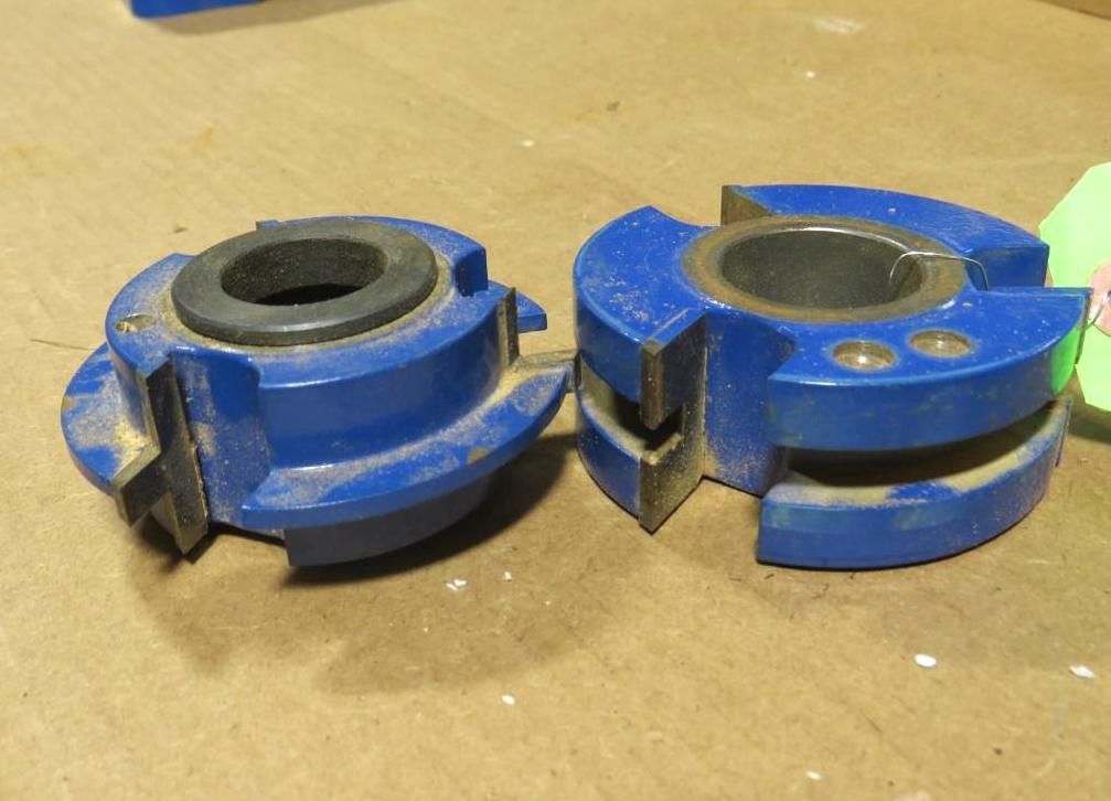 Two blue woodworking router bits on a wooden surface.
