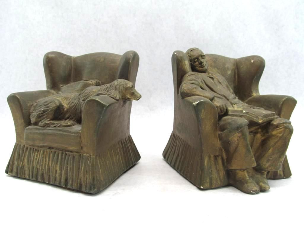 Two bronze-colored chair bookends: one with a sleeping dog, the other with a seated person reading.