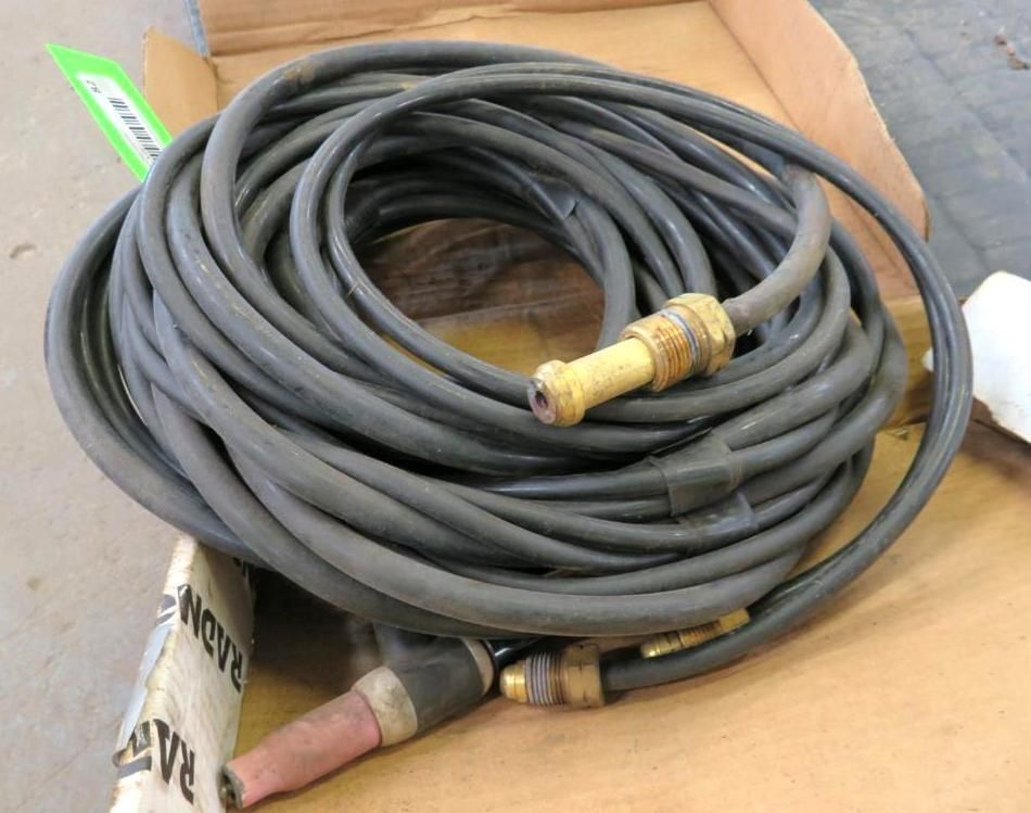 Coiled black welding hose with brass fittings and torch head.