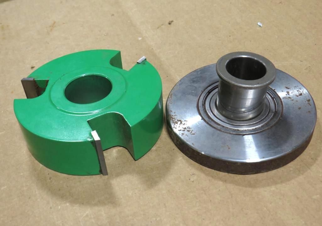 Green router bit next to a metal bearing. Both sit on a wooden surface.