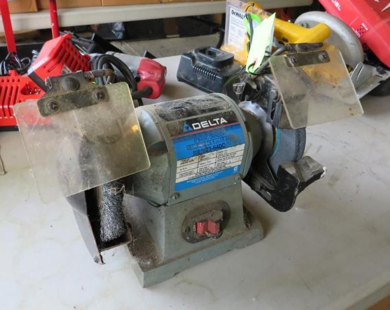 Delta bench grinder with safety shields on a workbench.
