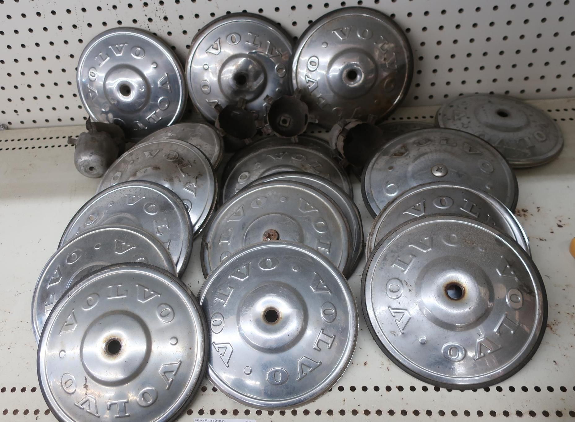 A collection of vintage, silver Volvo wheel covers, arranged on a shelf.