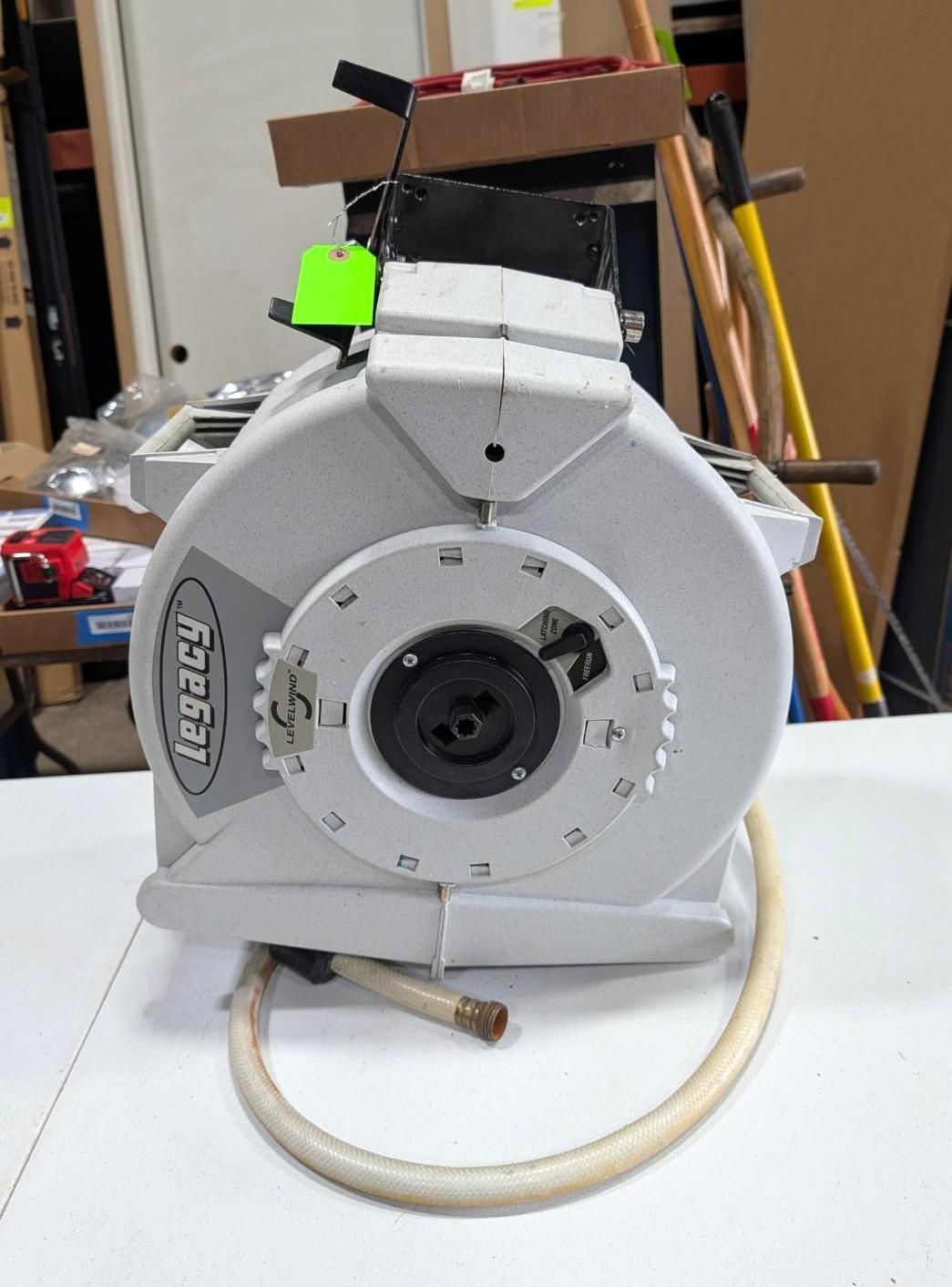 Gray industrial machine housing with a circular front opening and a coiled hose on a workbench.
