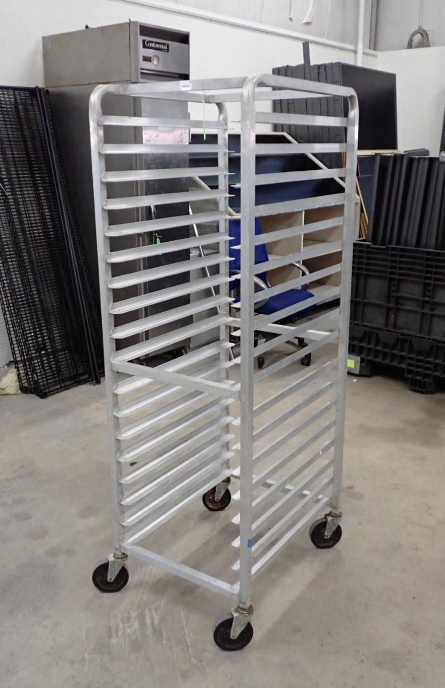 Empty aluminum rack on wheels, likely for baking sheets, in a warehouse setting.