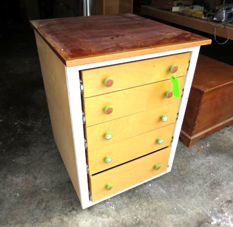 Small chest of drawers with five drawers. Light-colored wood drawers with green and red knobs.